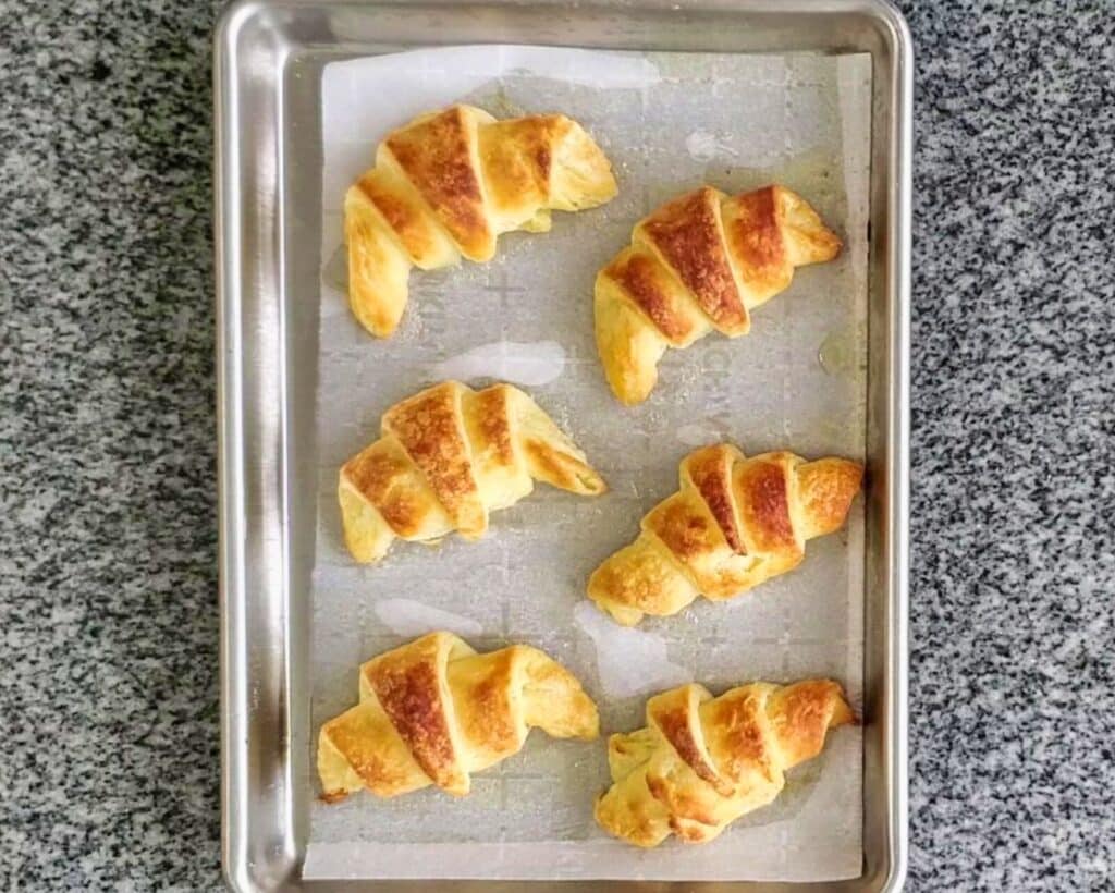 baked crescent rolls on parchment-lined baking sheet.