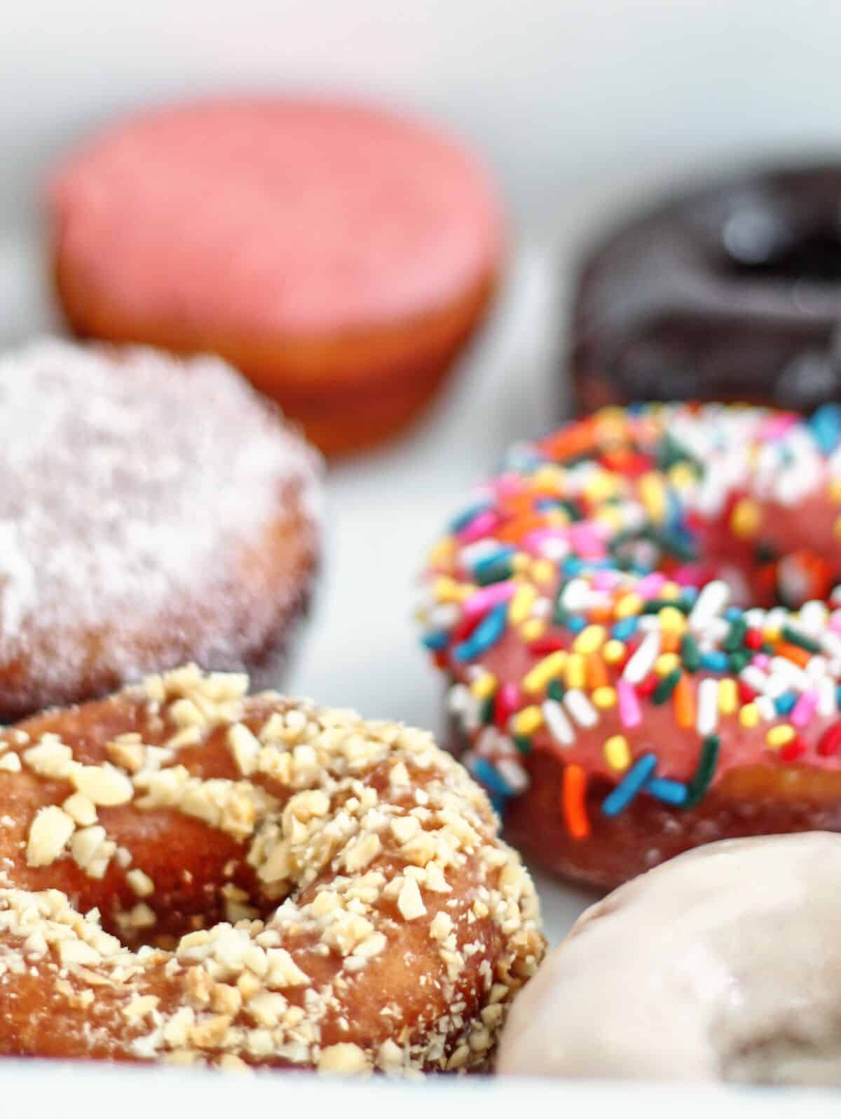 variety of gluten free yeast donuts in white box.