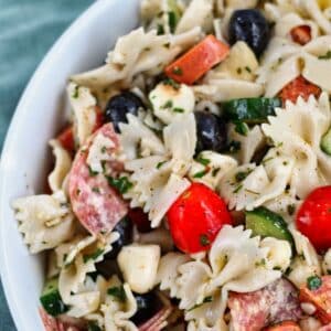 gluten free bowtie pasta salad in large white bowl with green towel in the background.