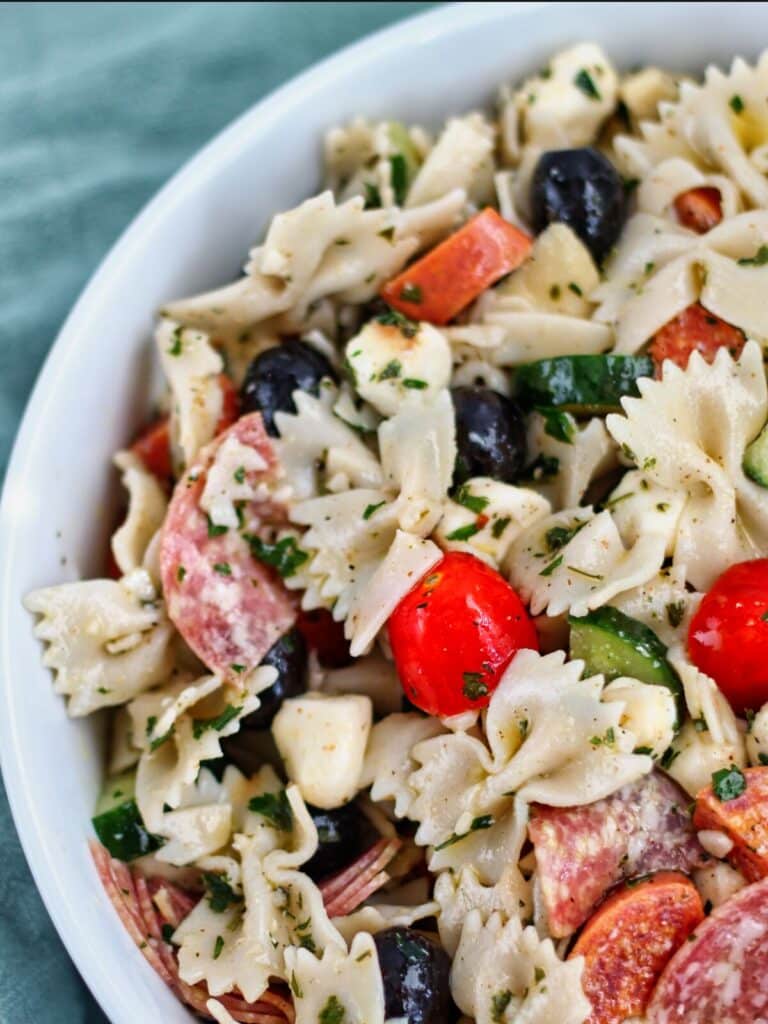 gluten free bowtie pasta salad in large white bowl with green towel in the background.