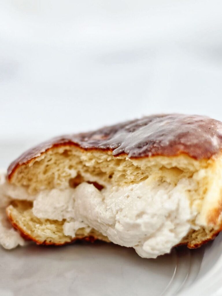 cream filled donut ripped open and up close on white plate.
