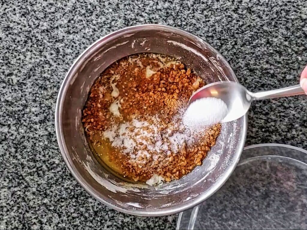 adding sugar to graham cracker crumbs in bowl.