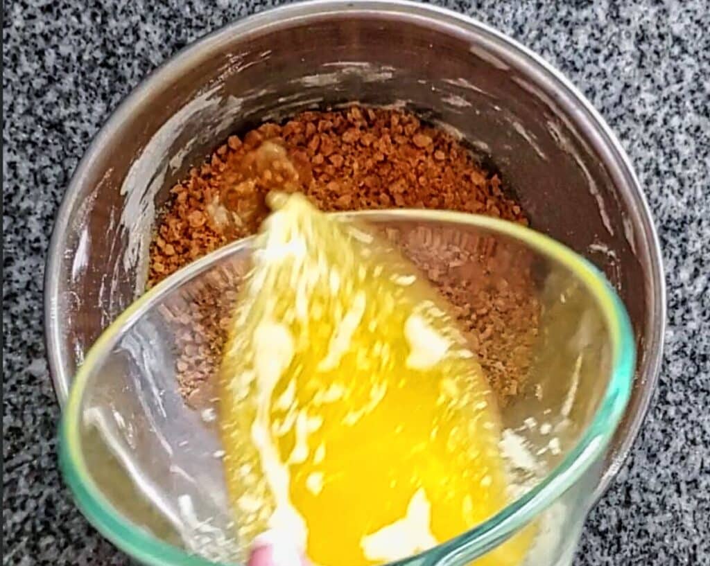 pouring melted butter onto graham cracker crumbs in small bowl.