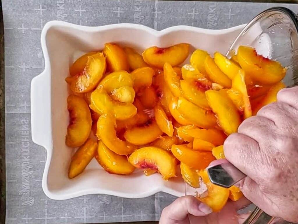 pouring peaches into baking dish.