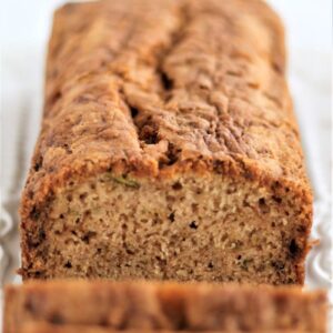 loaf of zucchini bread on white rectangular platter with a few slices cut