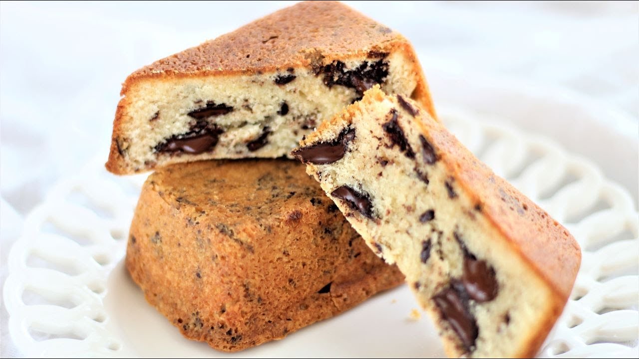 cut open cookie cake on top of whole cake on white scalloped plate.