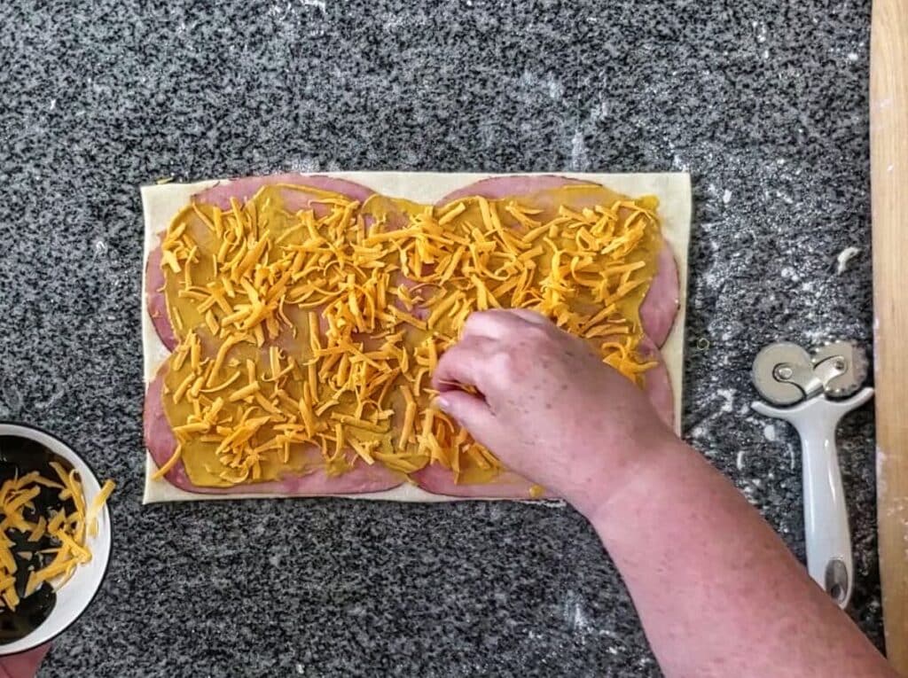 sprinkling cheddar cheese on top of mustard.