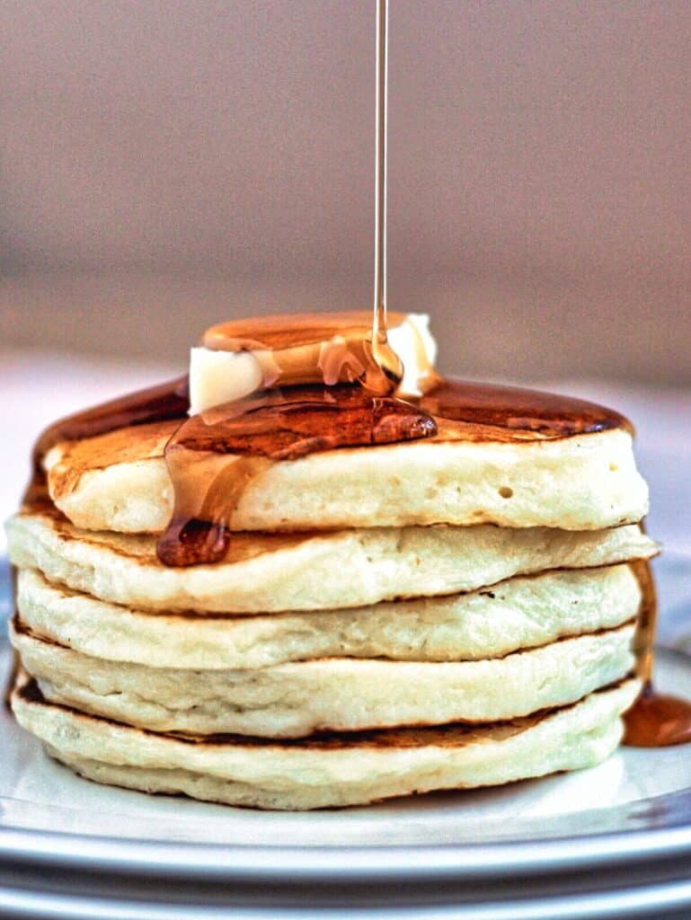 stack of gf fluffy pancakes drizzled with syrup.