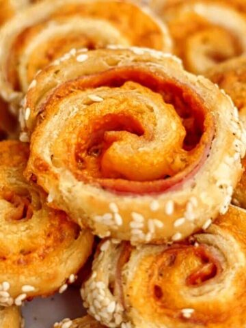 landscape view of white plate stacked with ham and cheese spirals.