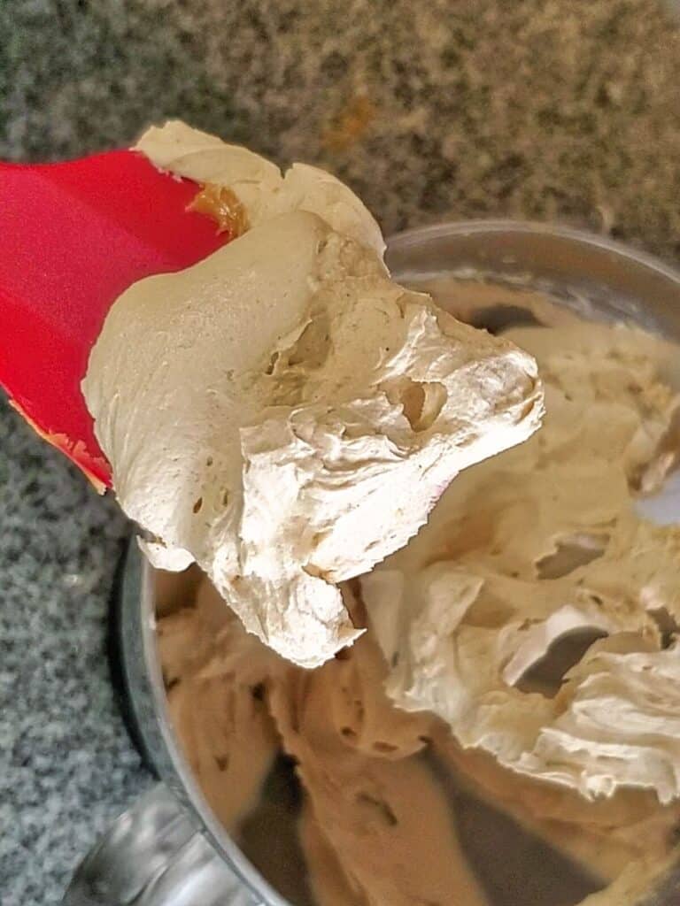 peanut butter buttercream just made and shown on red silicone spatula.
