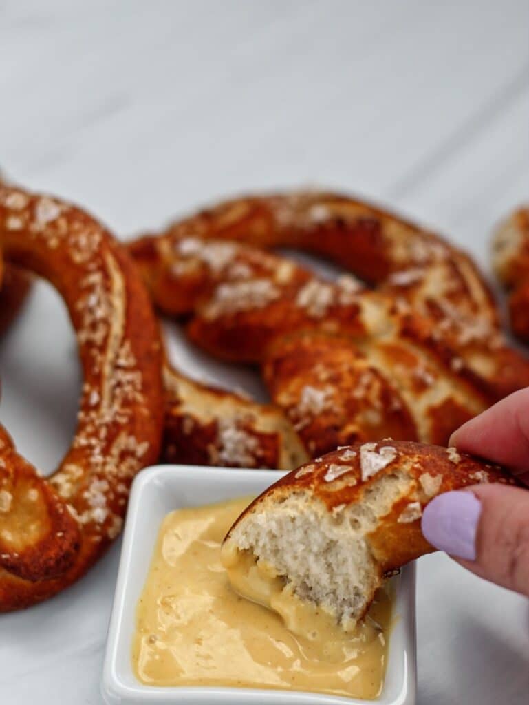dipping a piece of soft pretzel into honey mustard.