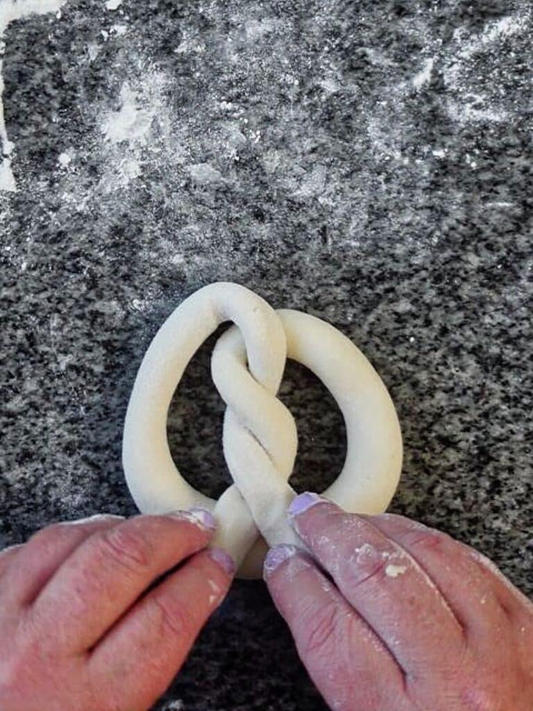 folding down ends of pretzel to meet the belly of the pretzel.