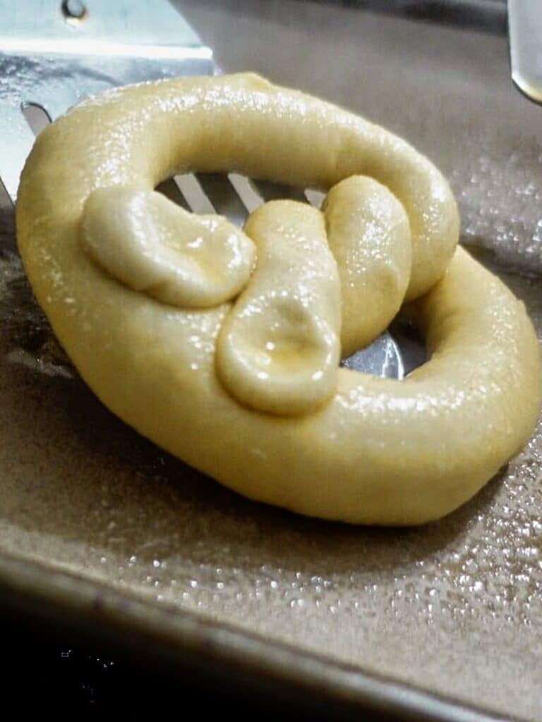 placing just boiled pretzel on greased parchment paper.