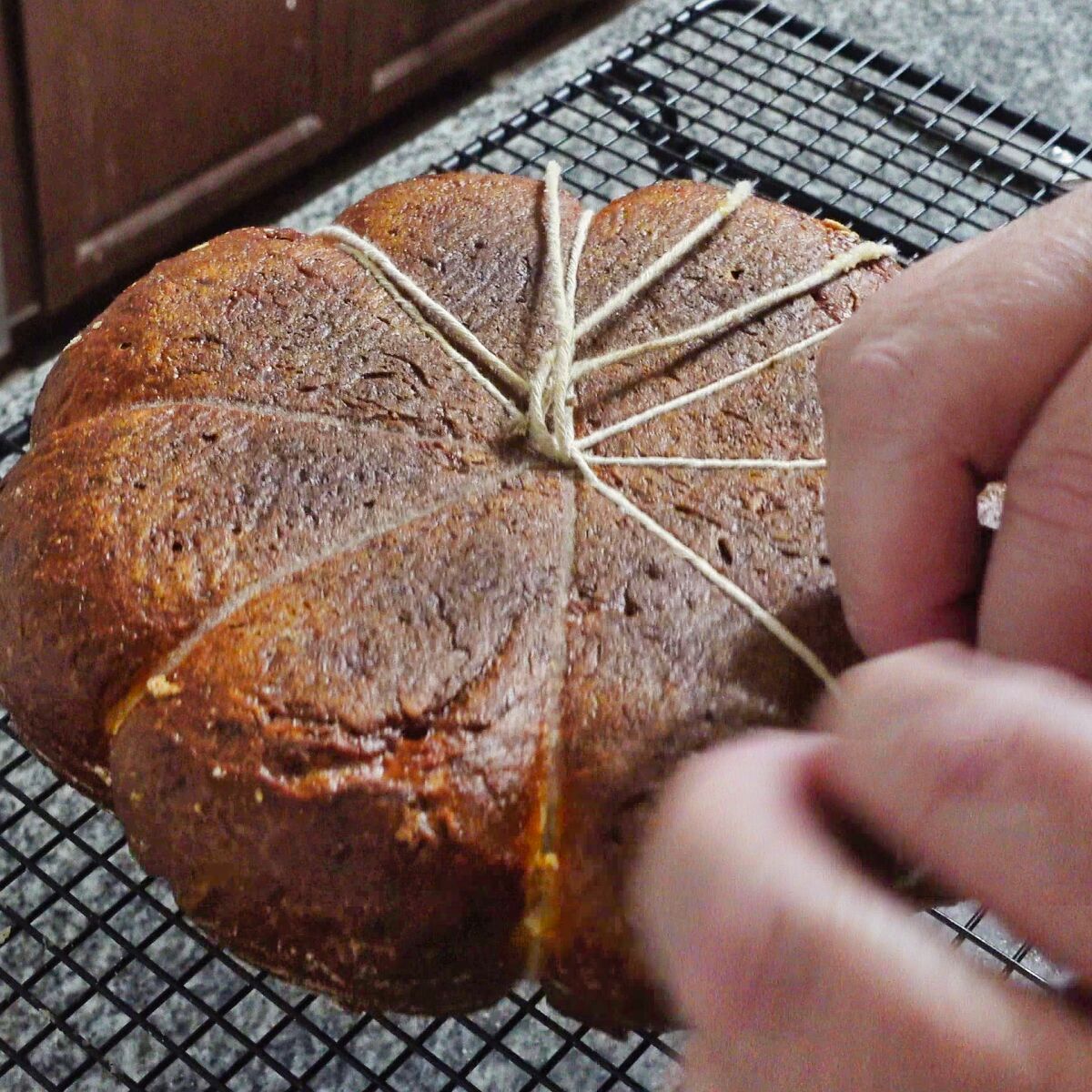 removing strings from bottom of baked bread on wire rack.