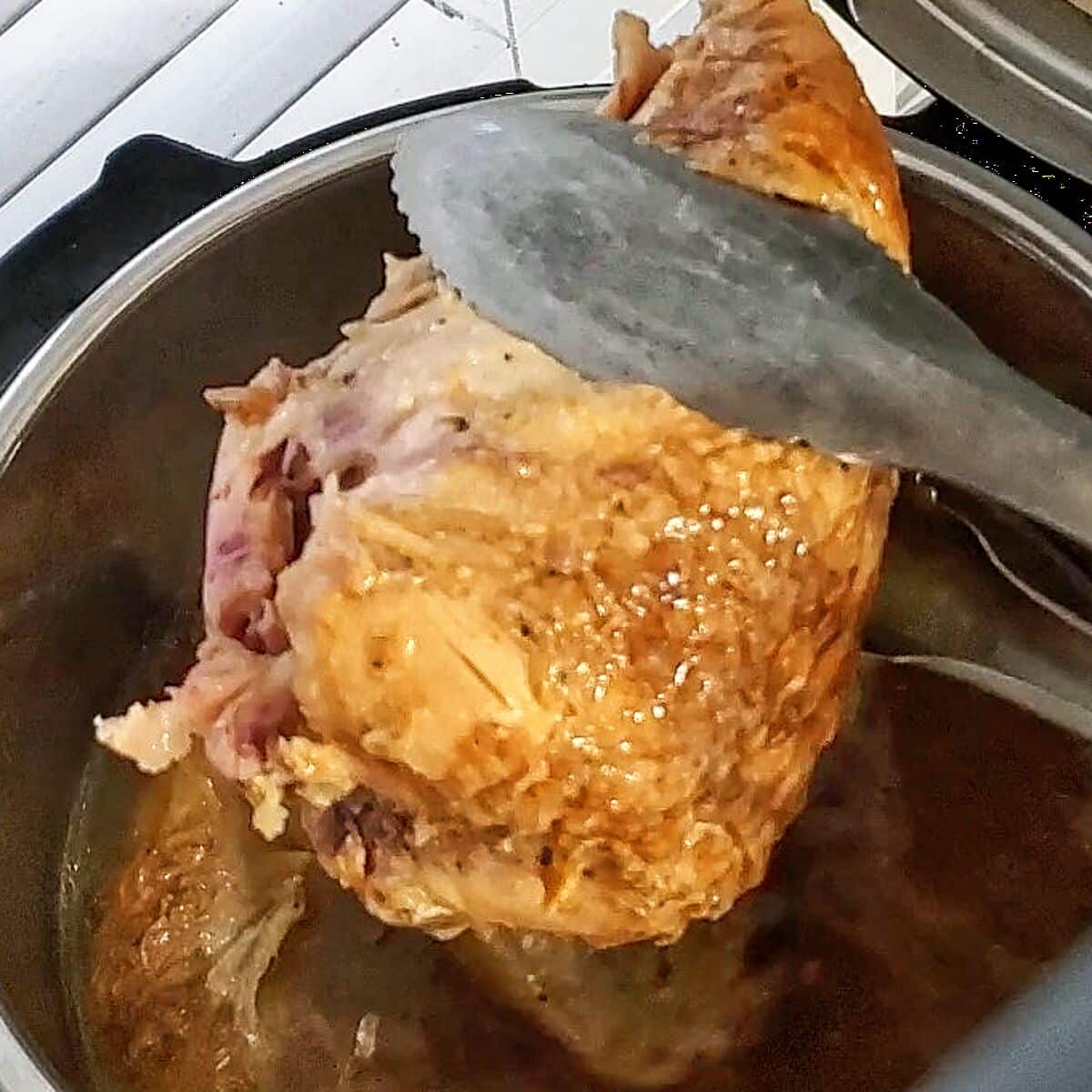 removing chicken from instant pot with tongs.