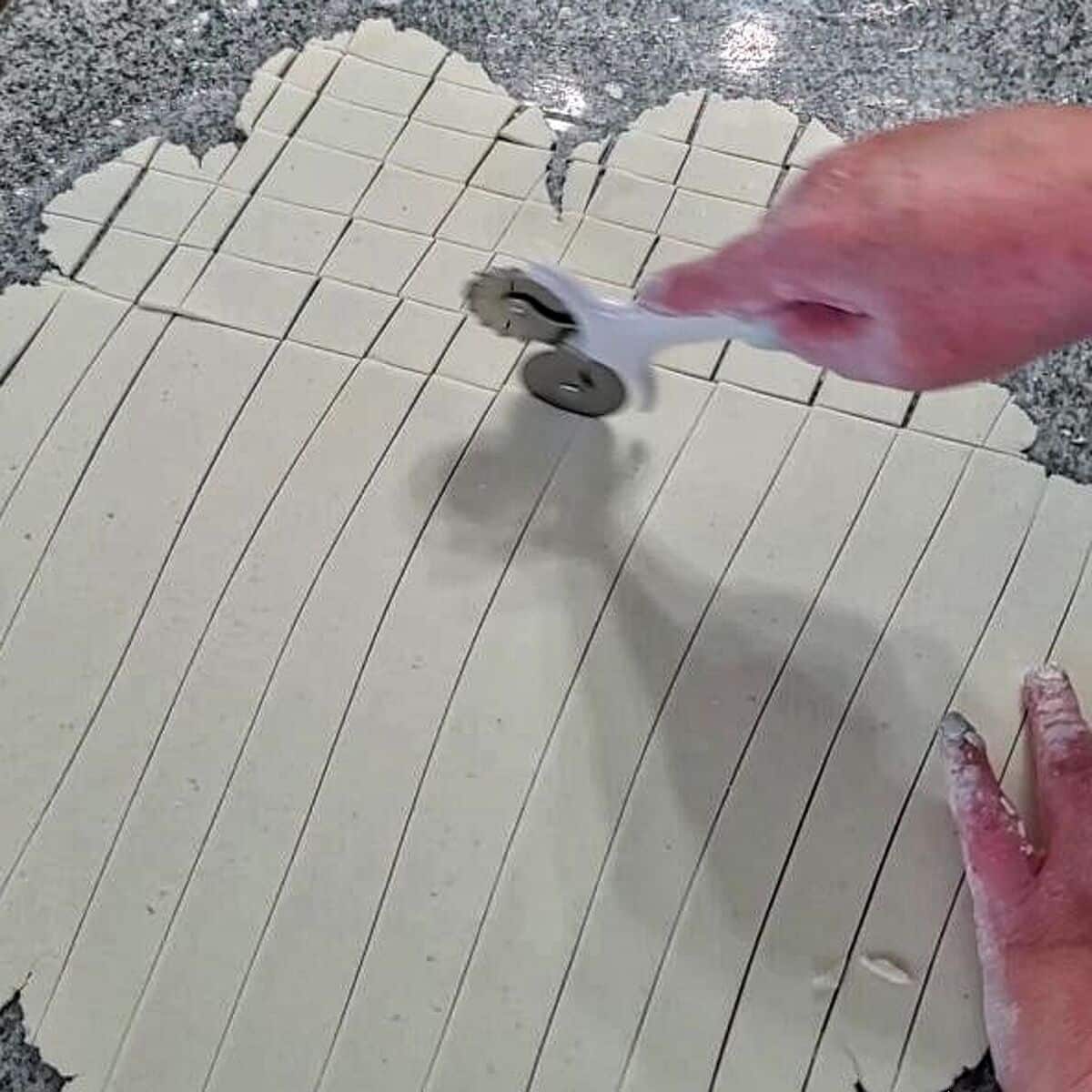 cutting dough into squares using a pastry cutter/wheel.