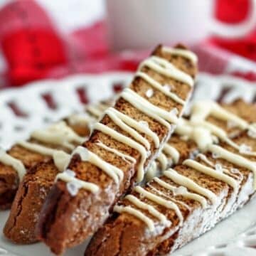 up close shot of several gingerbread biscotti on scalloped white plate.
