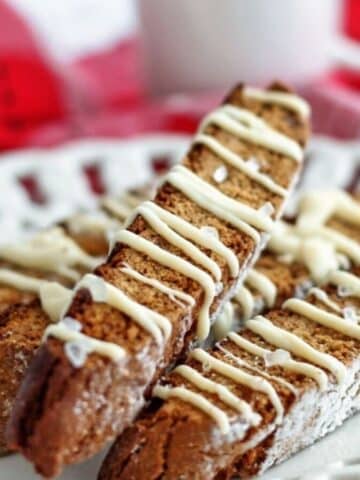up close shot of several gingerbread biscotti on scalloped white plate.