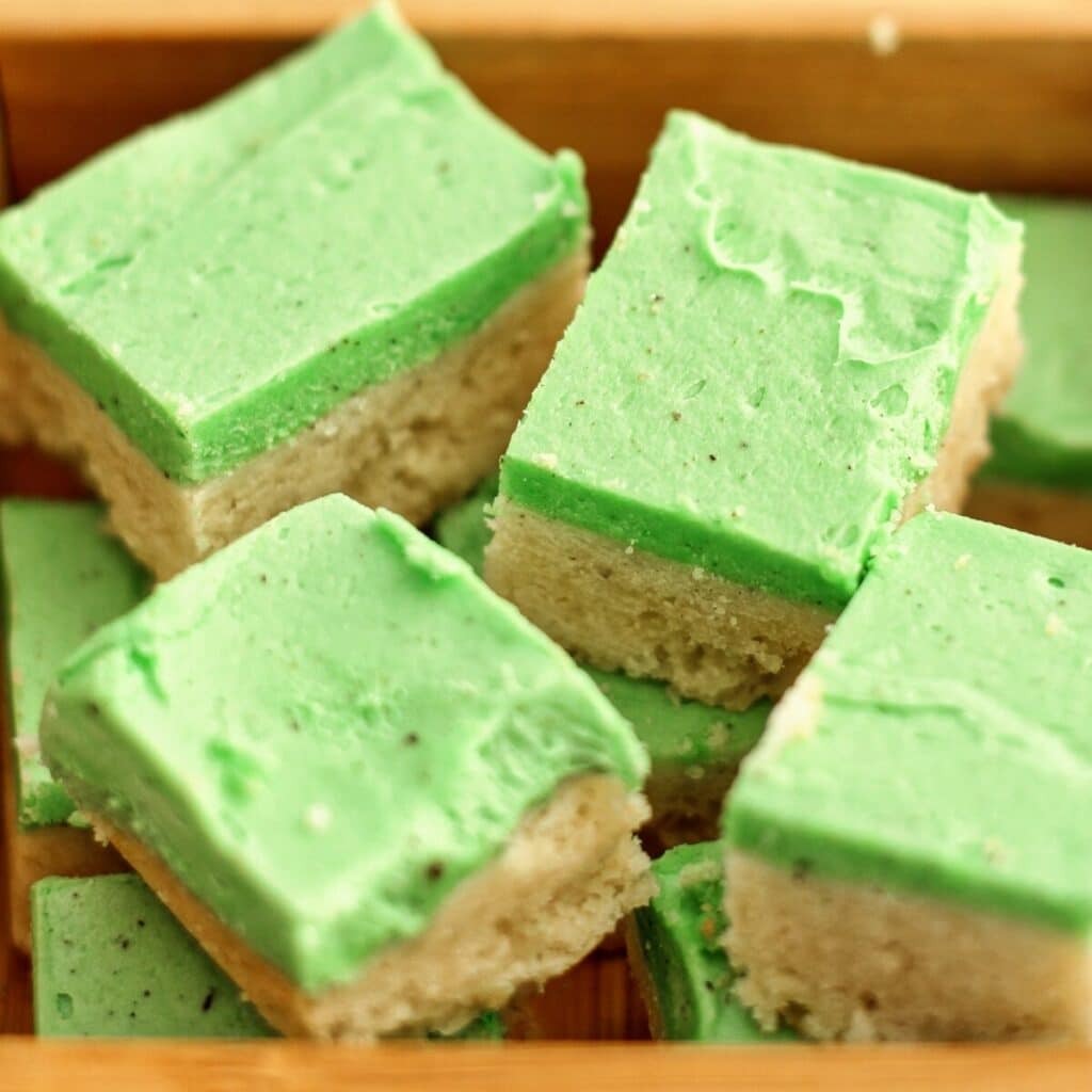 sugar cookie cubes with green frosting in wooden box.