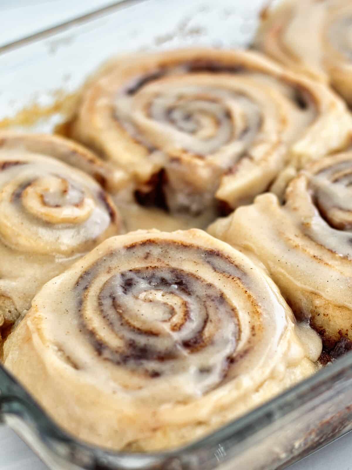 swirls of cinnamon rolls just baked with a light spread of frosting on top.