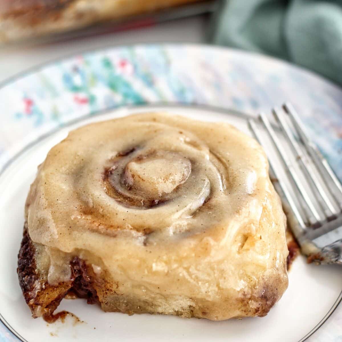 Whole cinnamon roll on pastel monet plate.