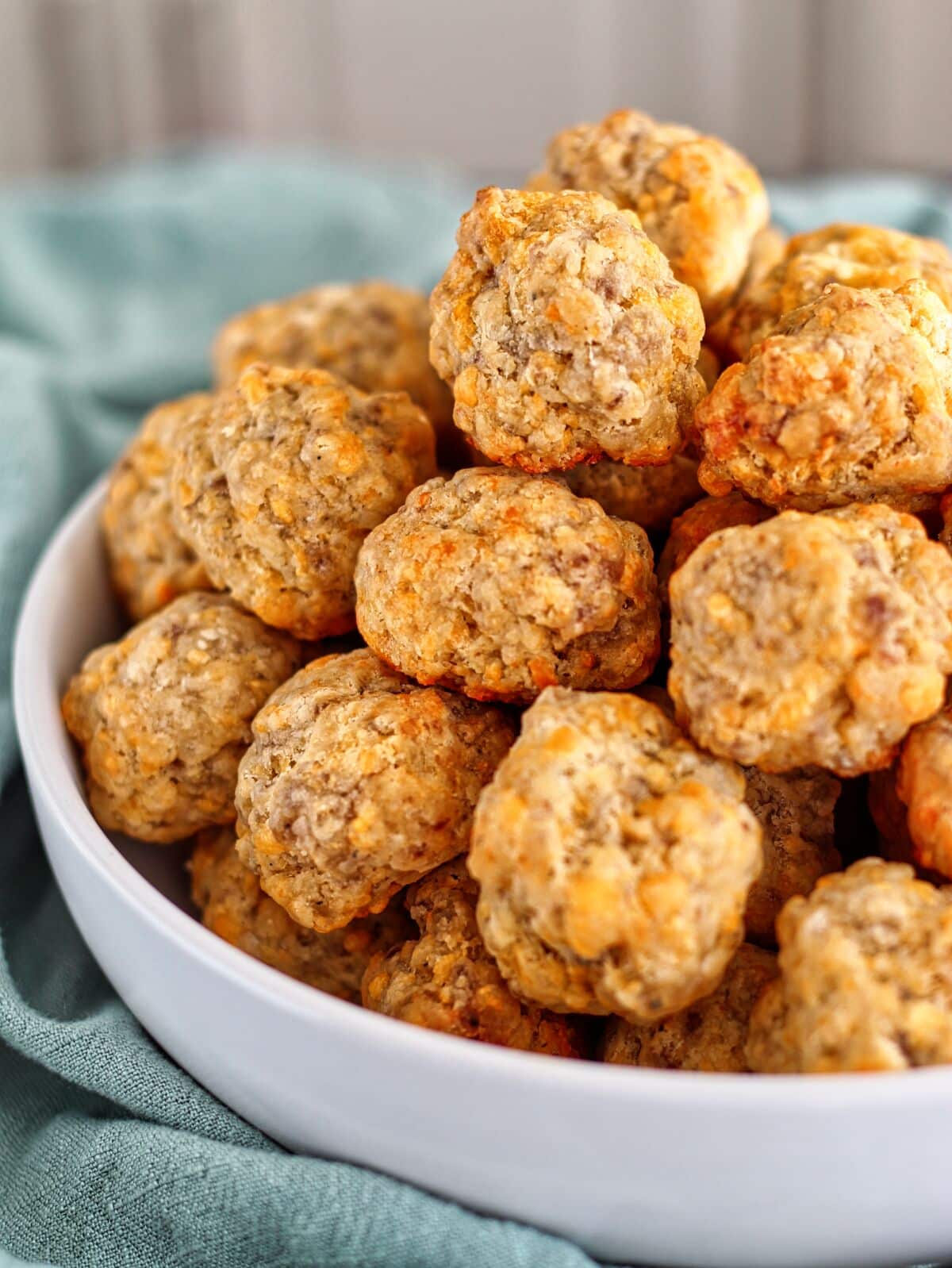 gluten free sausage balls in large white bowl with green towel  around it.