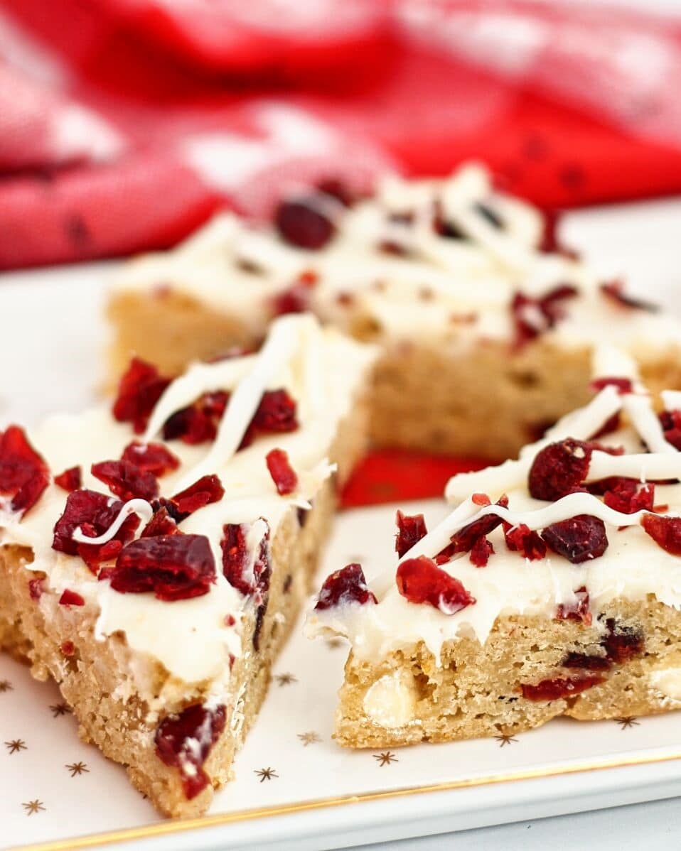 cranberry bars on white christmas platter with red towel in the background.