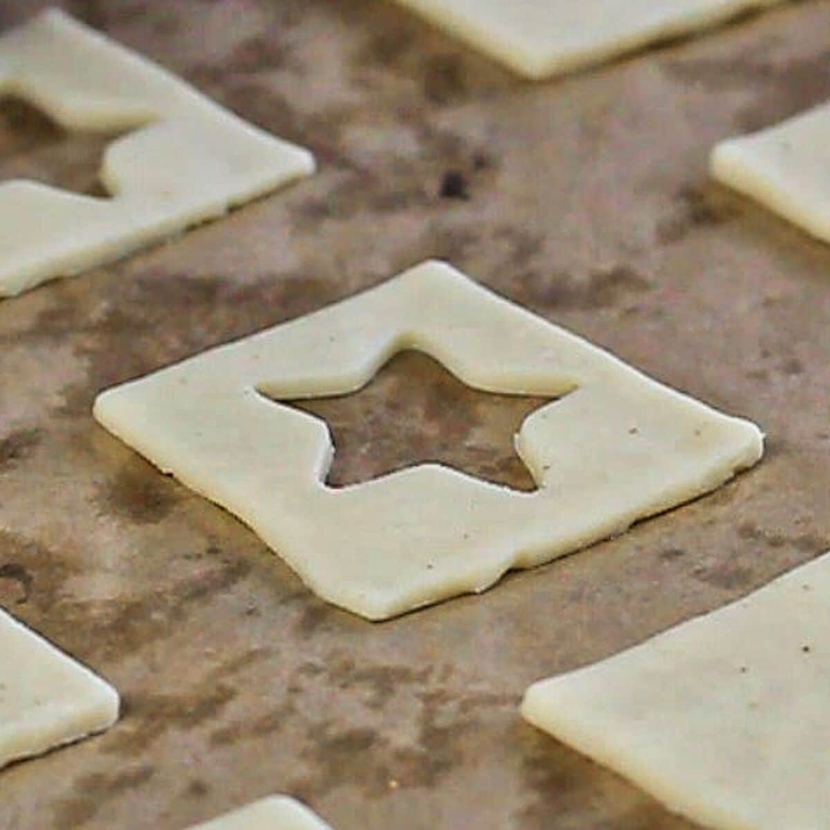 cutting stars out of the middle of square pieces of dough.