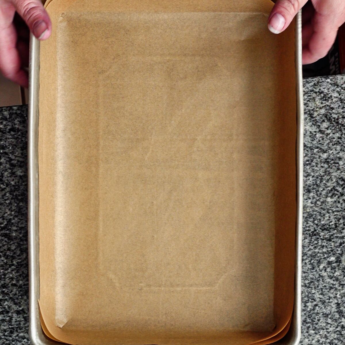 lining 9 by 13 inch baking pan with brown parchment paper.