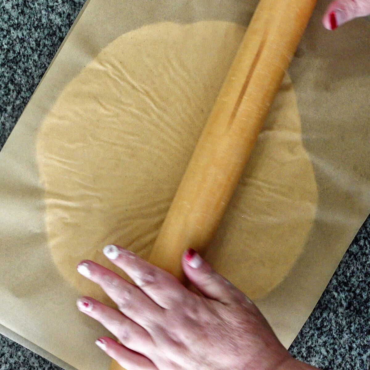 rolling dough between two sheets of brown parchment paper.