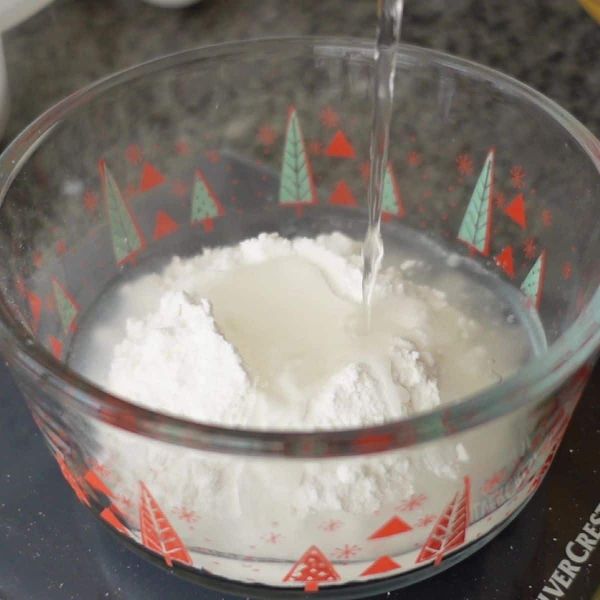 pouring boiling water over gf flour in glass bowl.