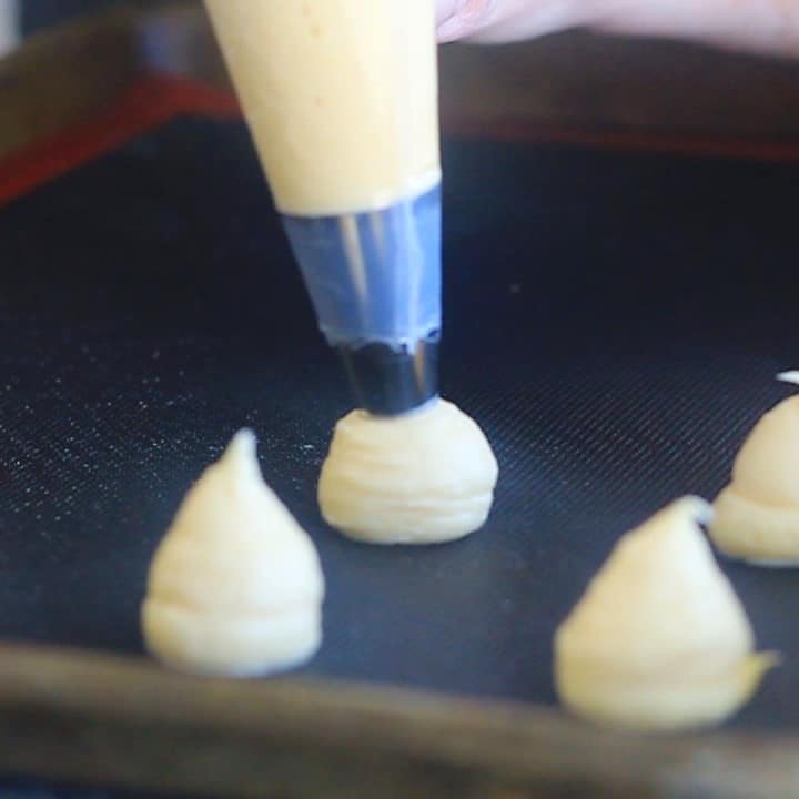 piping choux paste onto perforated silicone mat on baking sheet.