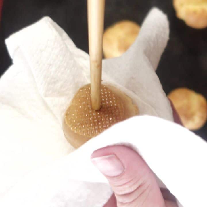 holding cream puff in paper towel while poking bottom with chopstick. 