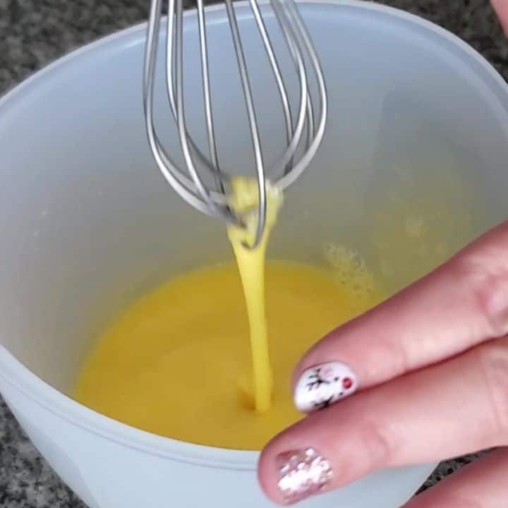 whisking eggs in silicone measuring cup.