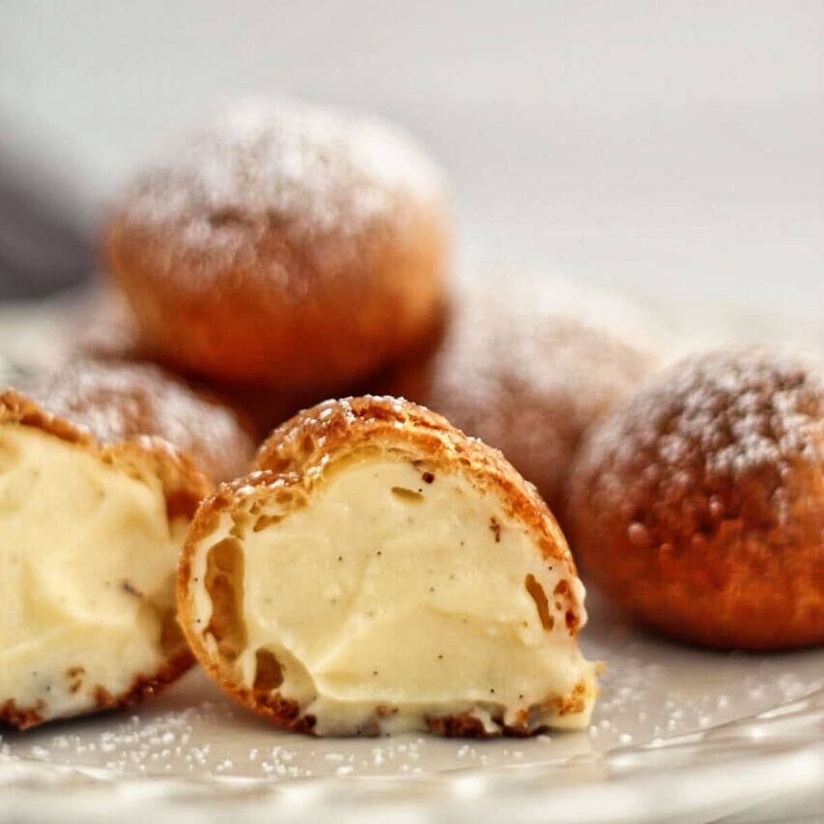 filled cream puffs cut open to reveal pastry cream on the inside.