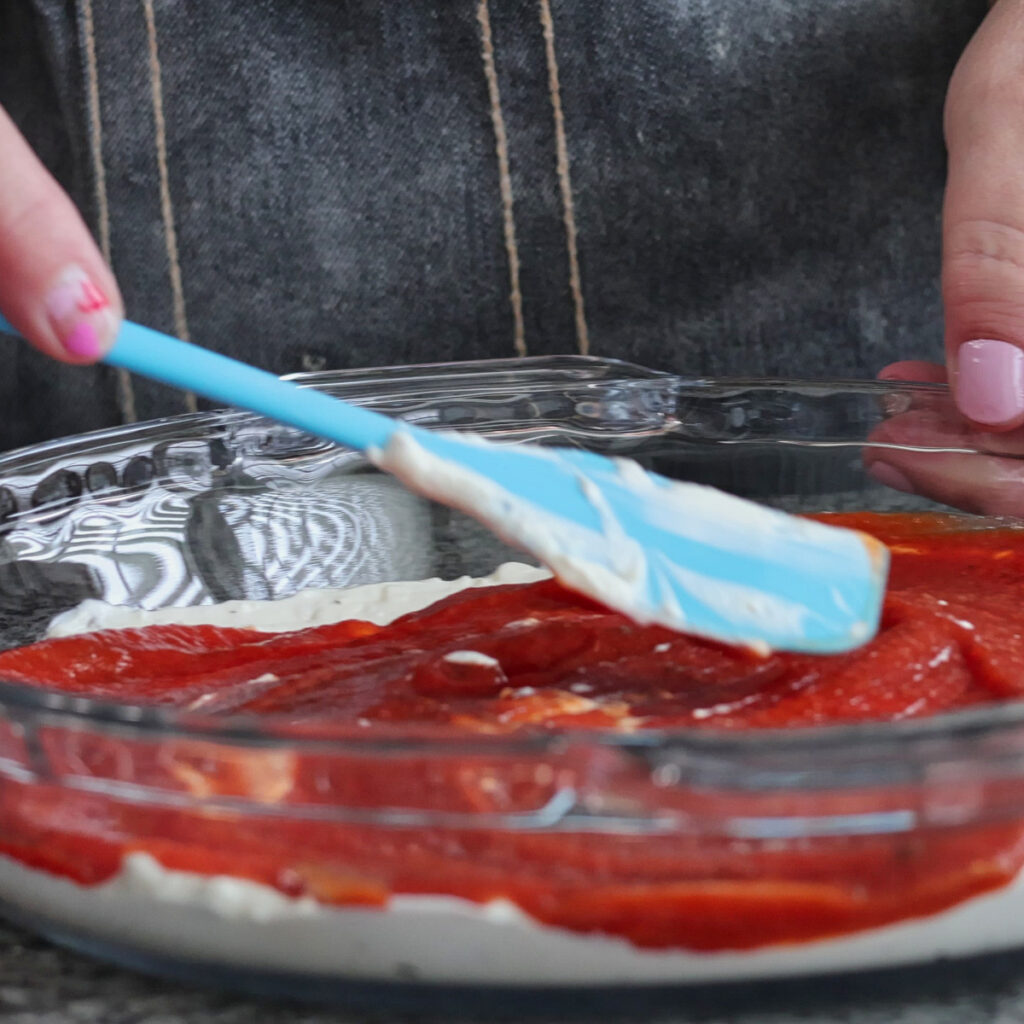 sprinkling shredded cheese on pizza dip