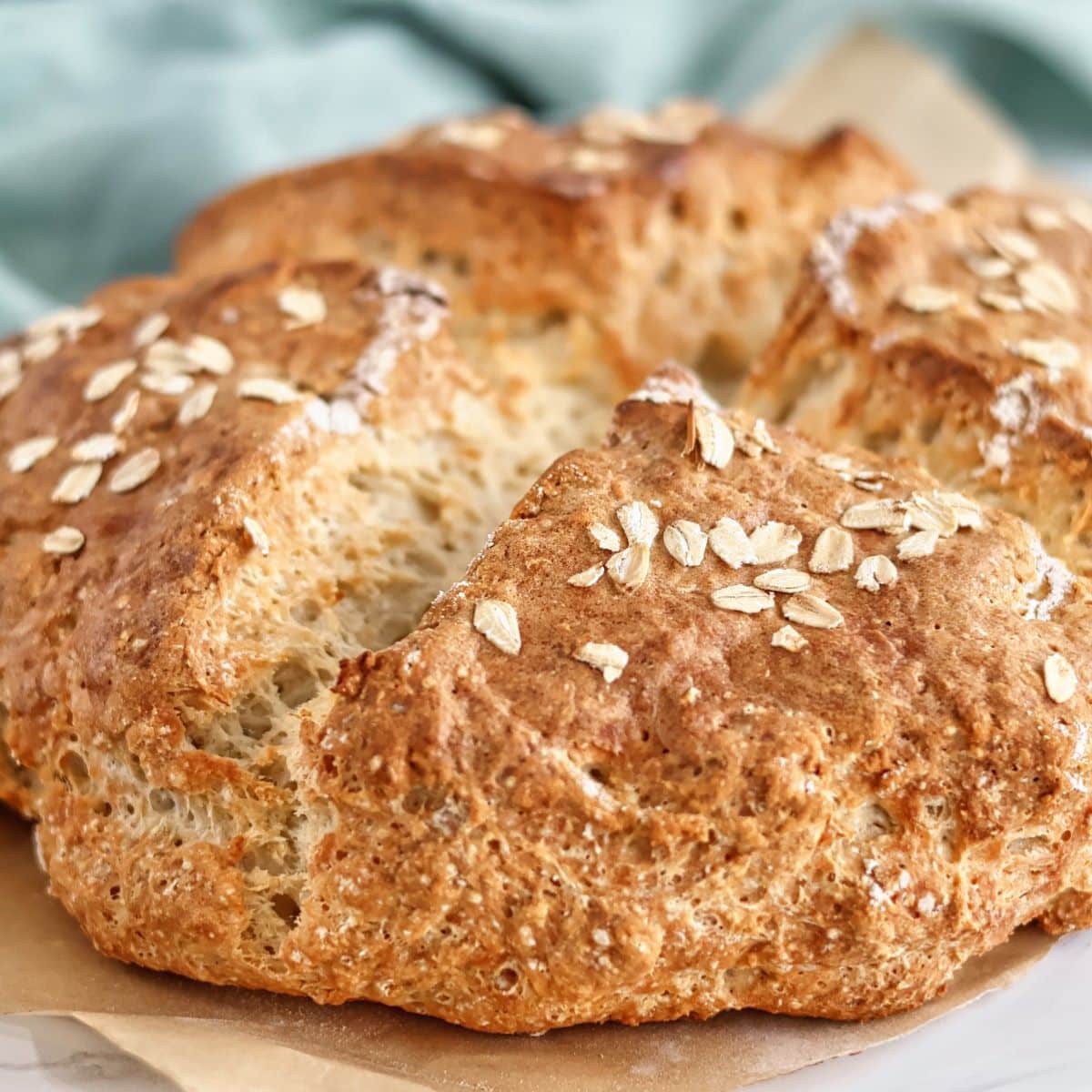 irish brown bread on brown parchment with green tea towel in the background.