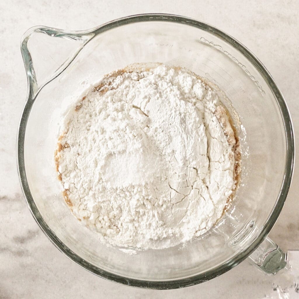 all ingredients for bread in glass mixing bowl.