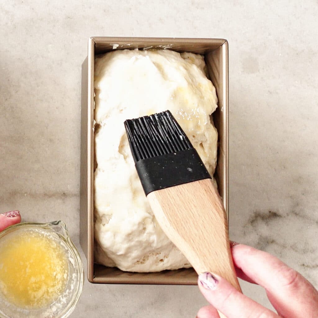 brushing melted butter onto risen dough.