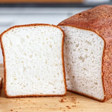 gluten free sandwich loaf on cutting board with one slice cut out of it and propped up next to it.