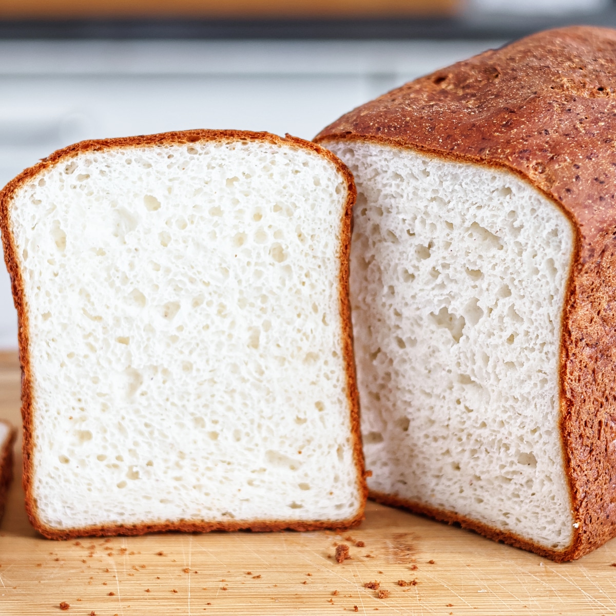 gluten free sandwich loaf on cutting board with one slice cut out of it and propped up next to it.  