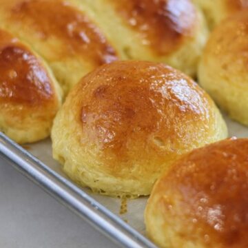 gluten free brioche buns on stainless steel baking rack.