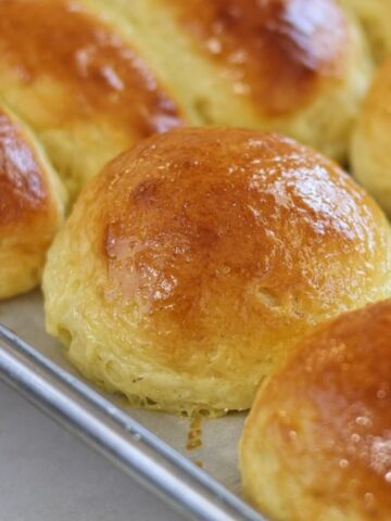 gluten free brioche buns on stainless steel baking rack.