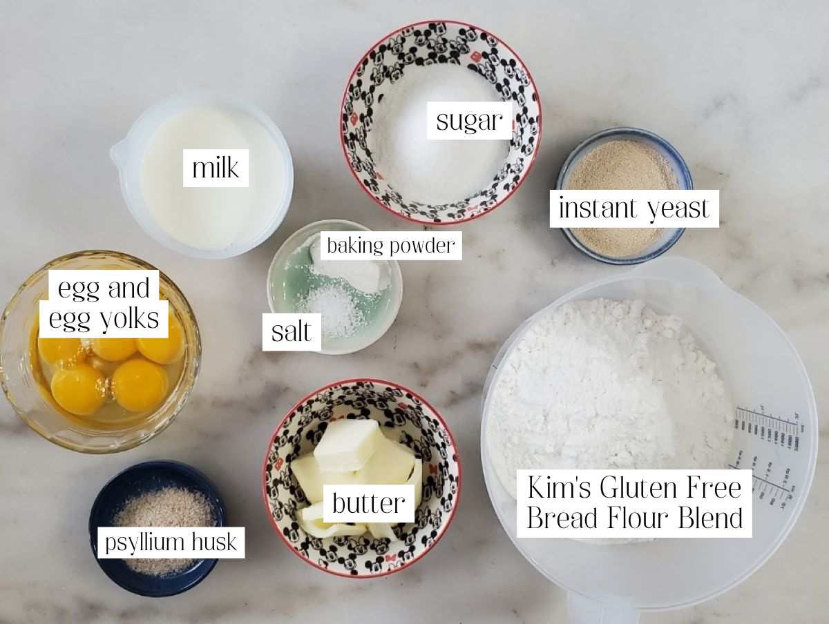 ingredients for brioche buns measured out and labeled on marble surface.