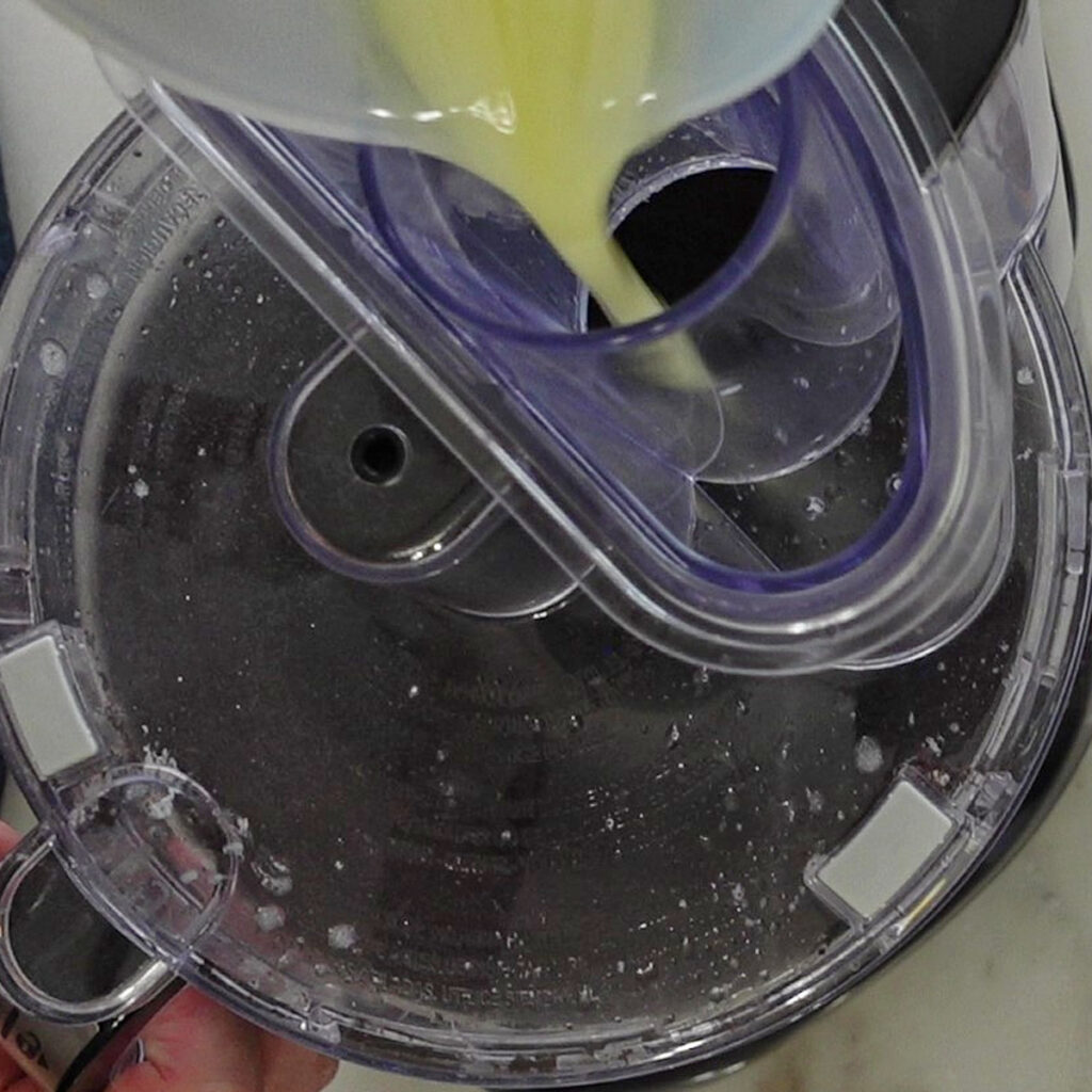 pouring melted butter into oreo crumbs in food processor.