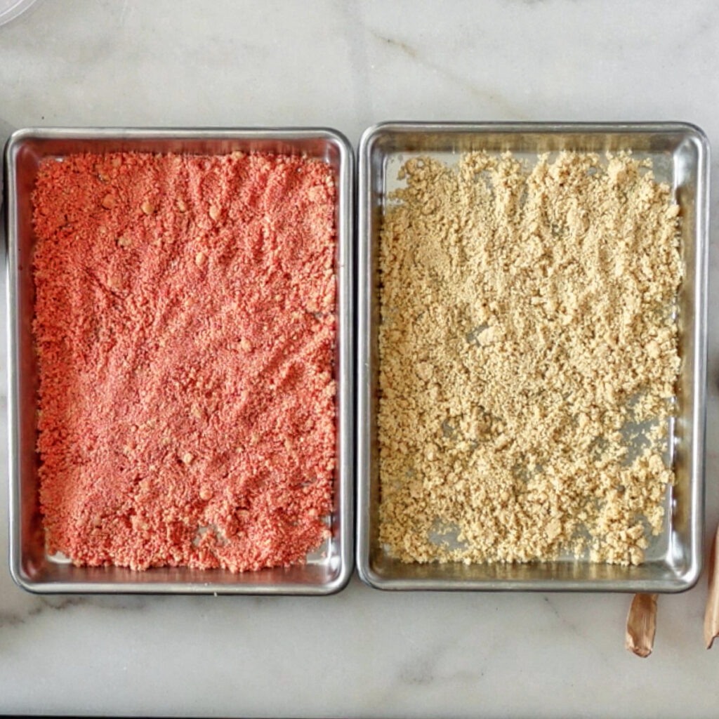 strawberry and vanilla cookie crumbs on two baking sheets.