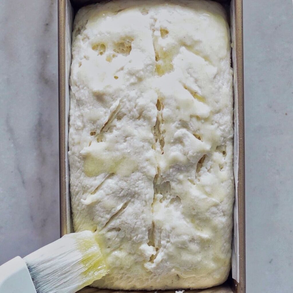brushing risen loaf with melted butter.