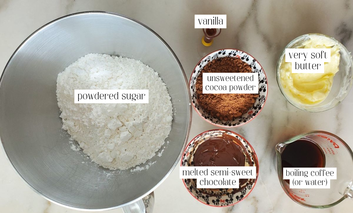 fudge frosting ingredients measured out and labeled on white marble countertop.