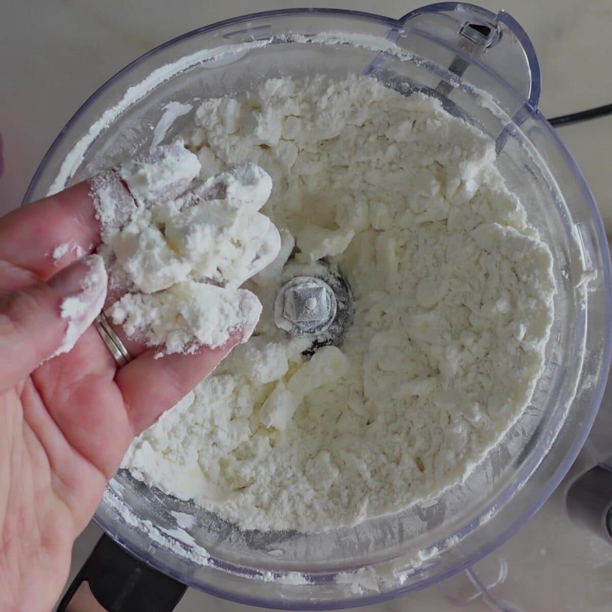 showing broken up butter in flour mixture in hand.