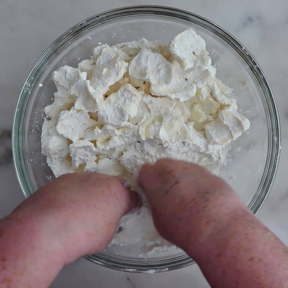 flattening chunks of butter into flat pieces with fingers.